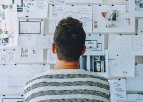 A man stands in front of a wall filled with creative ideas and plans. Ideal for innovation themes.